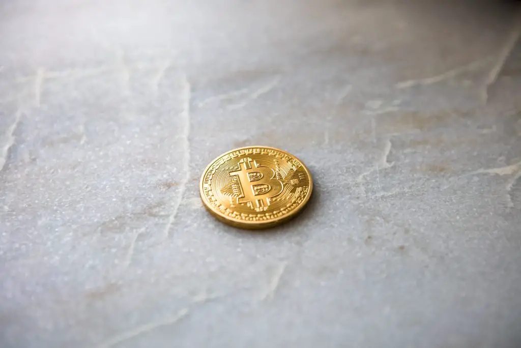 a representation of a "bitcoin", in the form of a coin, sitting on grey surface. 