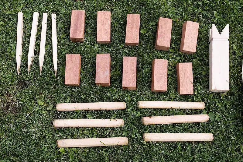 overhead view of wooden Kubb pieces; 10 wooden kubb blocks, 6 wooden batons, one kubb king piece and 4 stakes