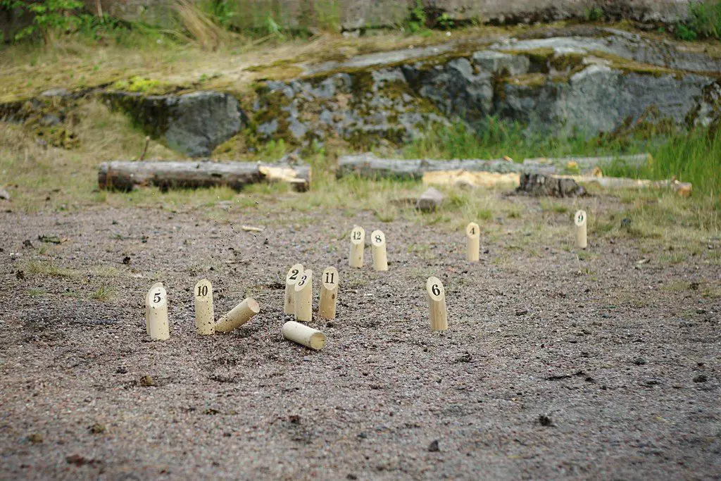 mölkky wooden dowels in the dirt, displaying an action shot of mölkky game play