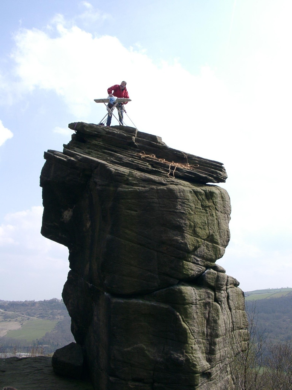 strange hobby extreme ironing, man on top of tall rock formation ironing