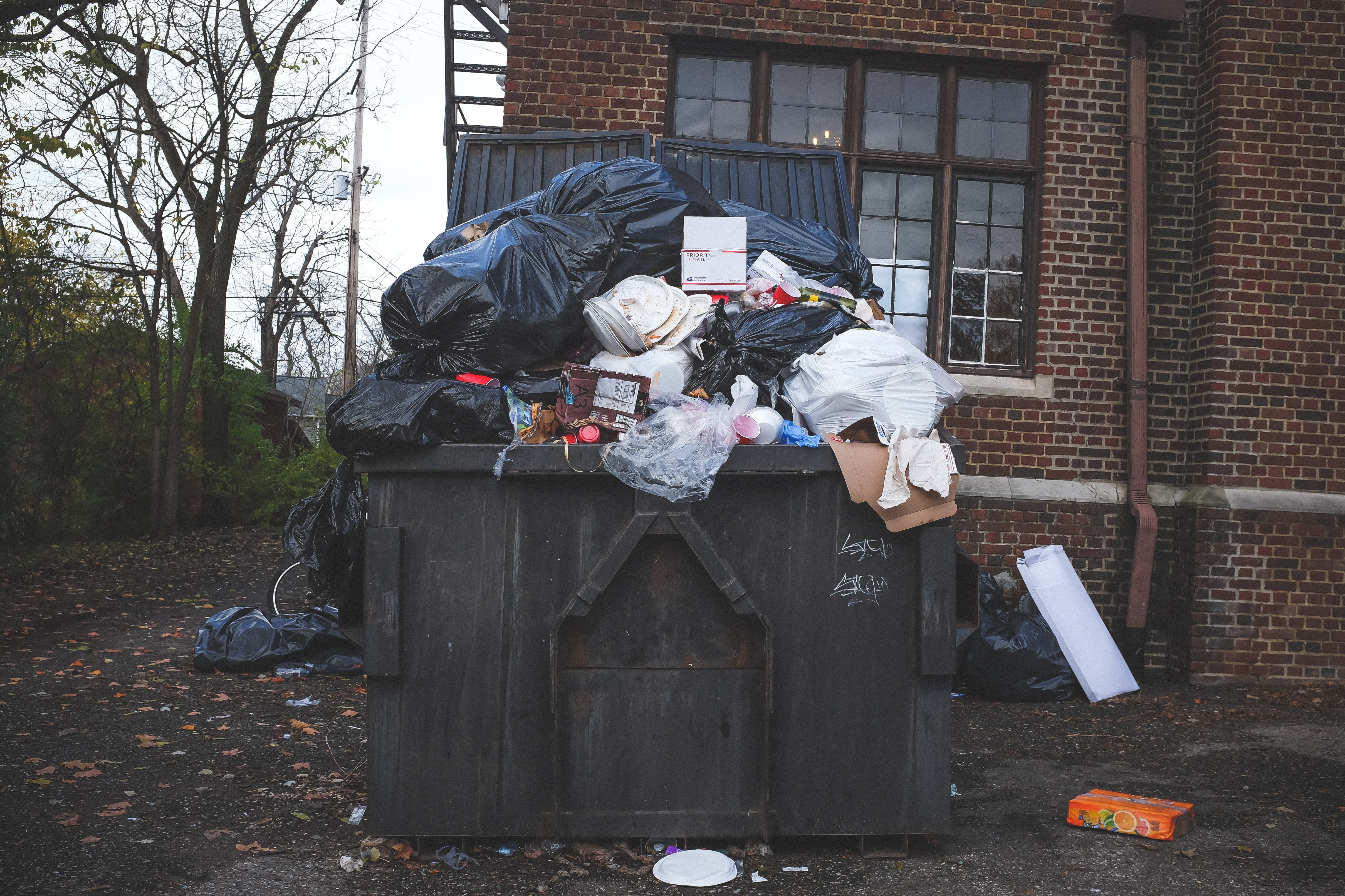 front view of an overflowing dumpster infront of red brick building