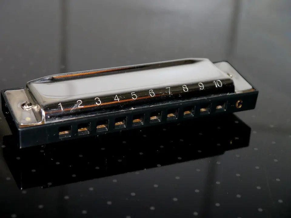 learn to play harmonica with this key of C, pictured on black table