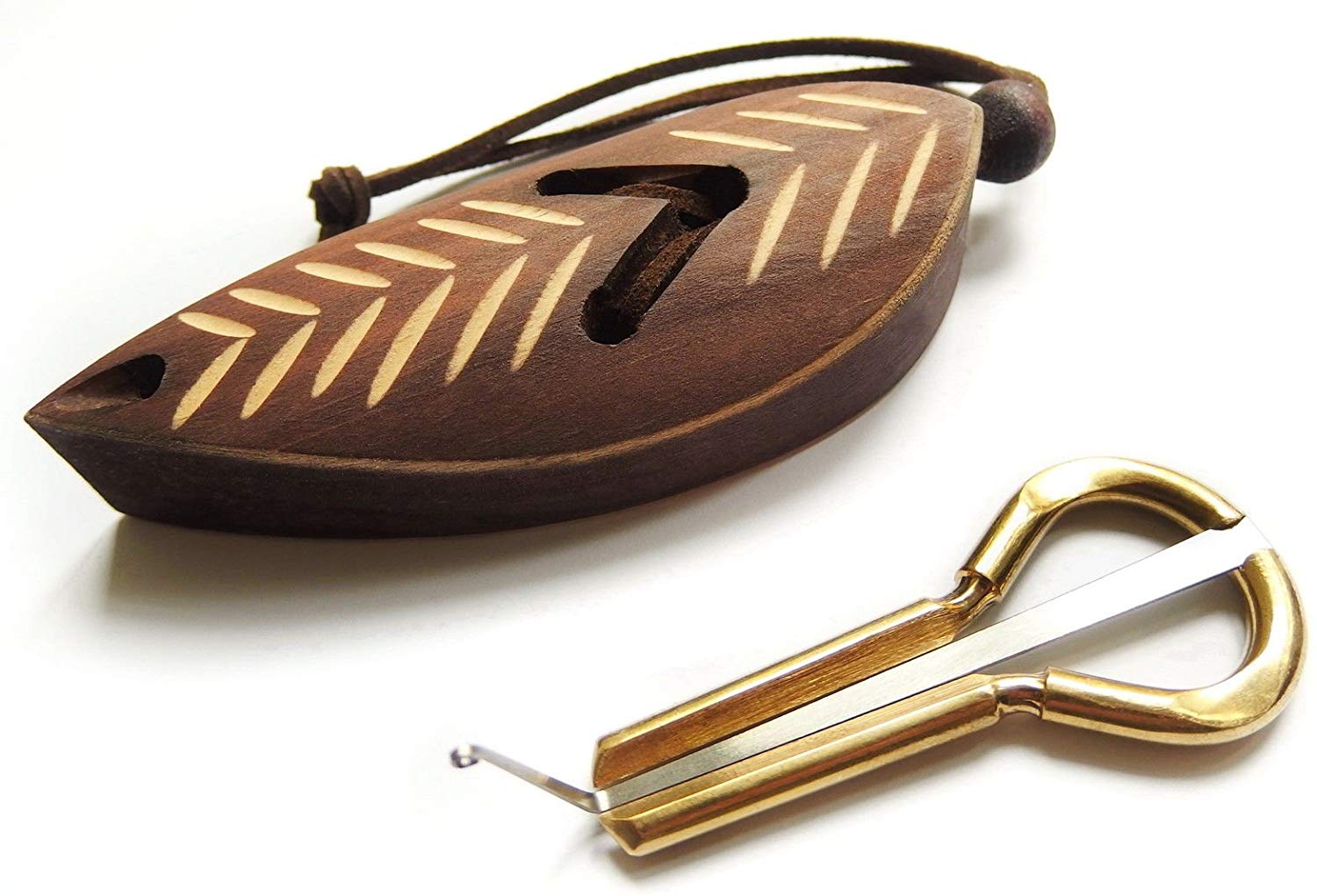 gold colored jaw harp and wooden case on blank white background