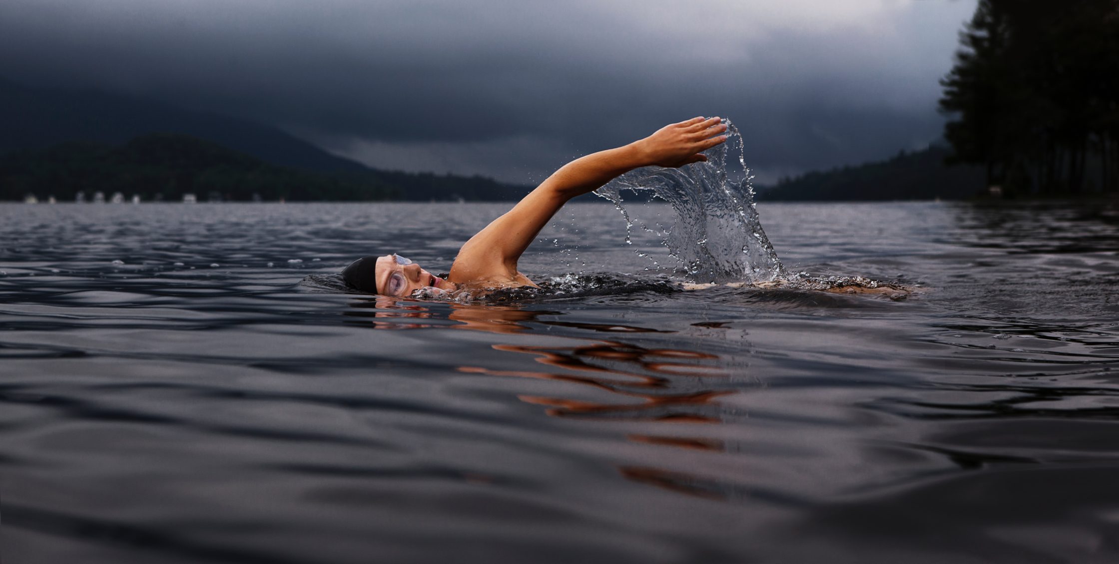 man swimming outdoors in dark water