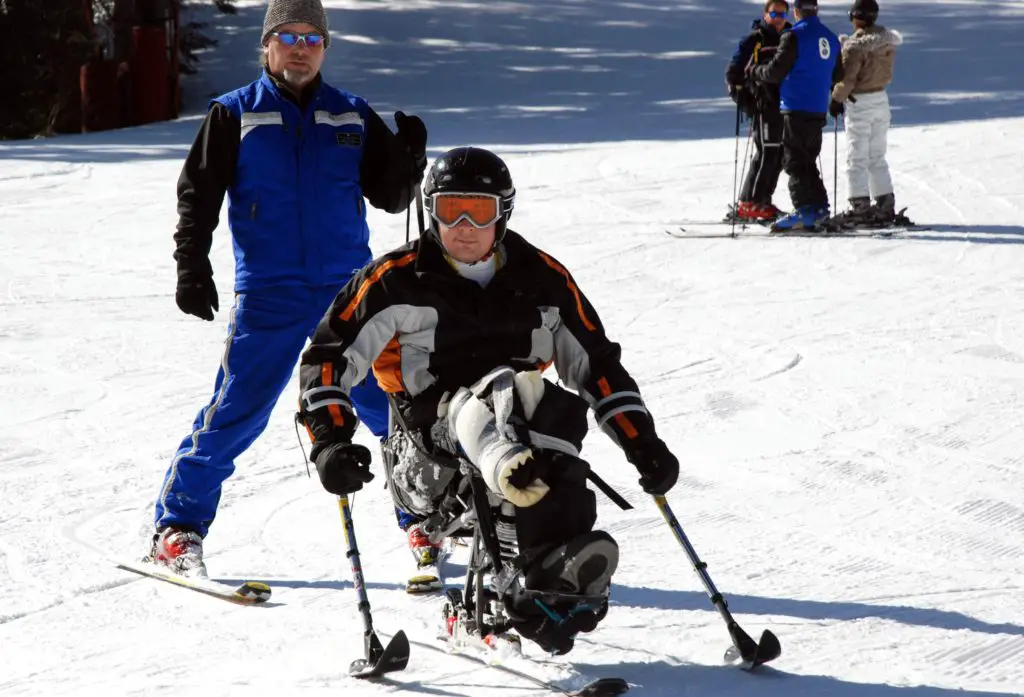 adaptive skiing, sit skiing with guide standing behind