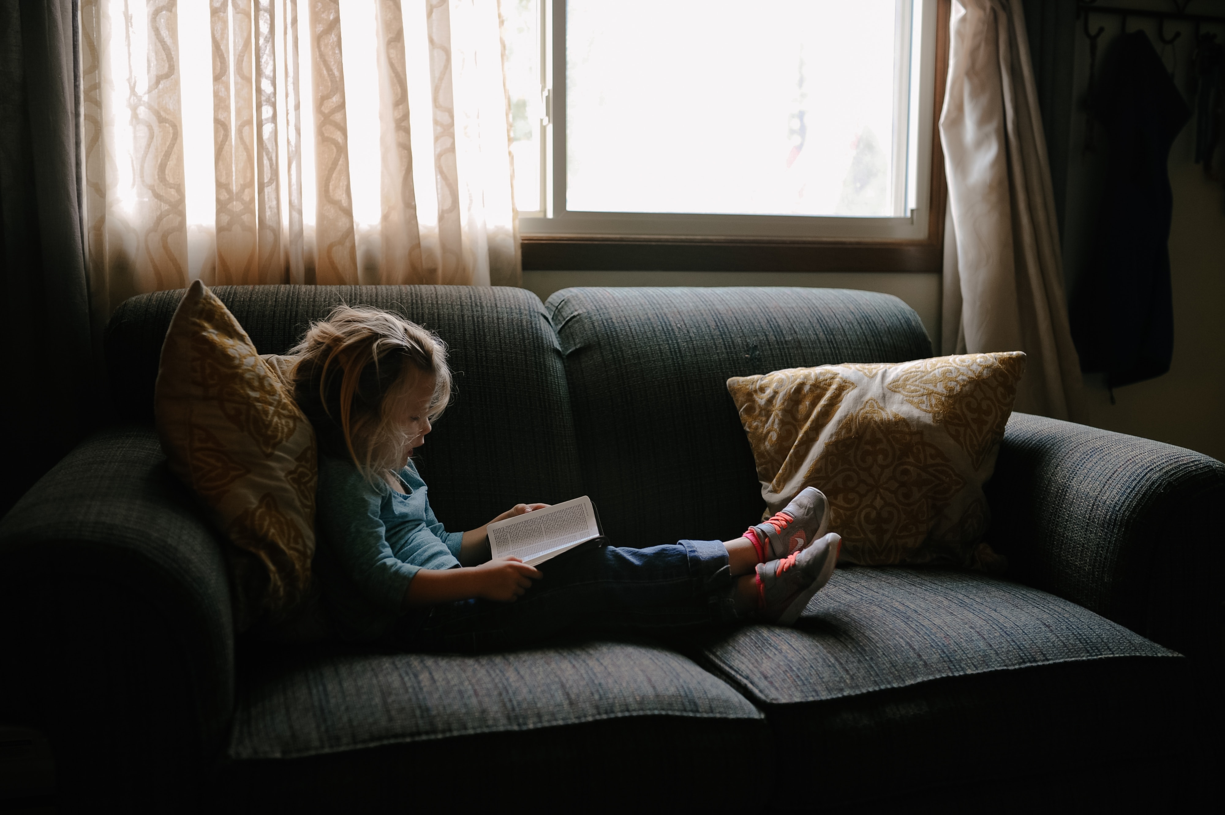 child on couch reading a book