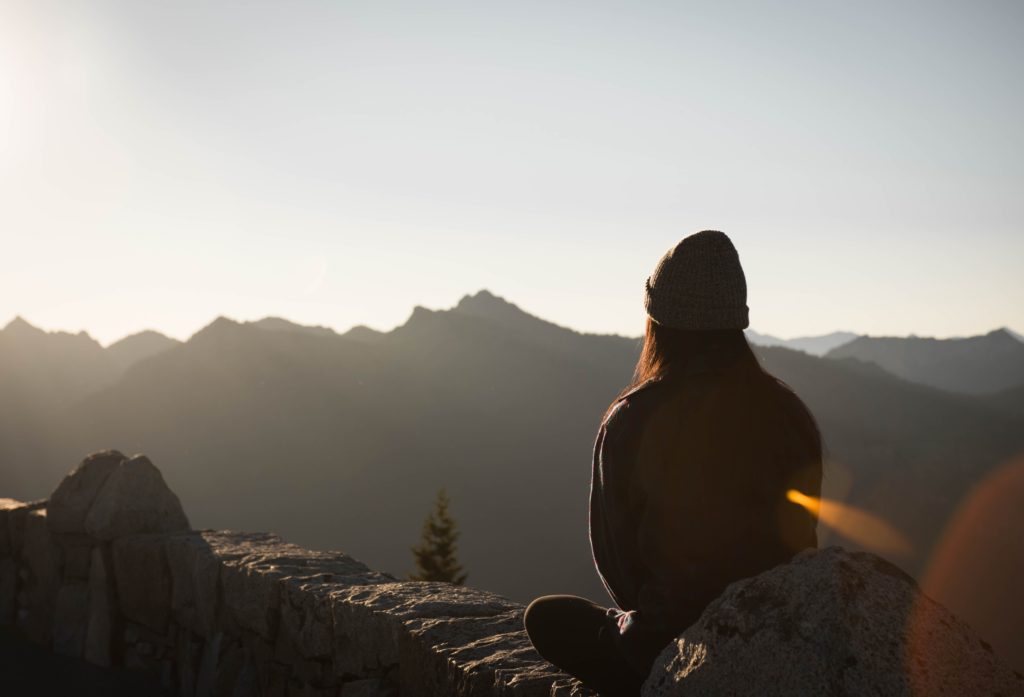 woman meditation outdoors, overlooking mountain landscape