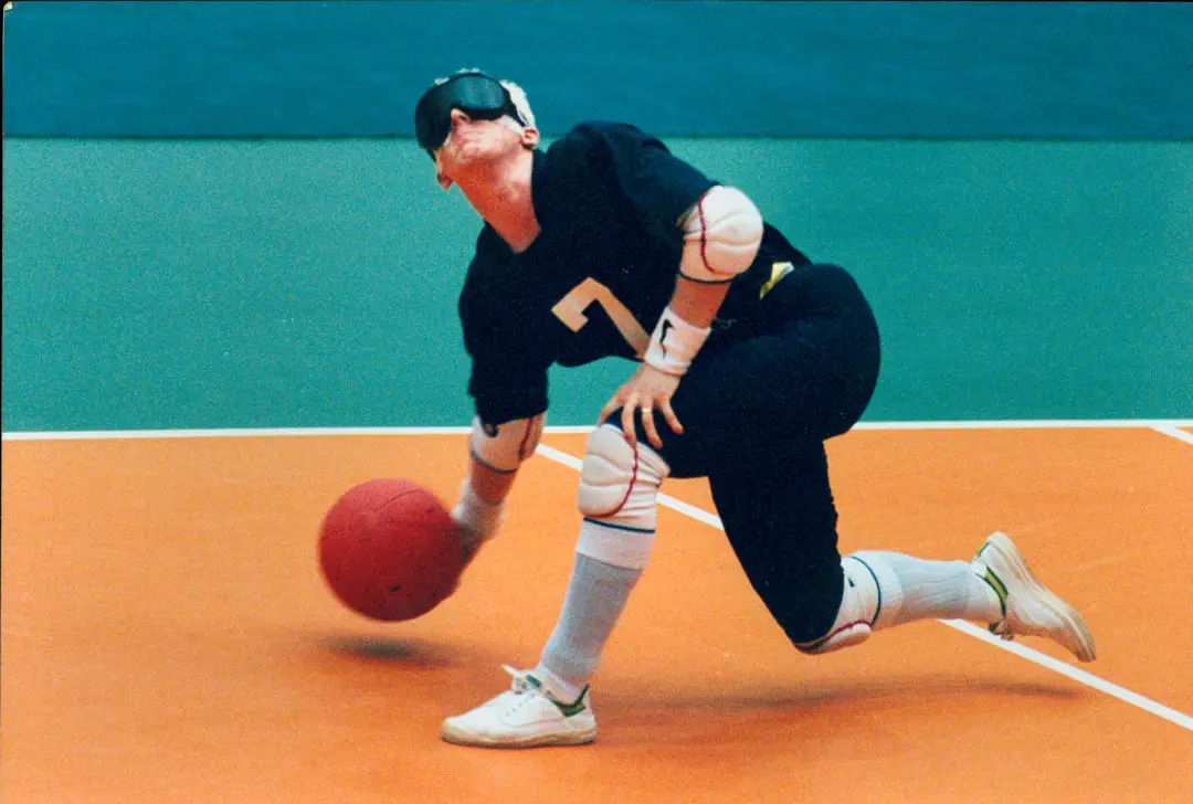 popular adaptive sport goalball, man throwing goalball with blinder on