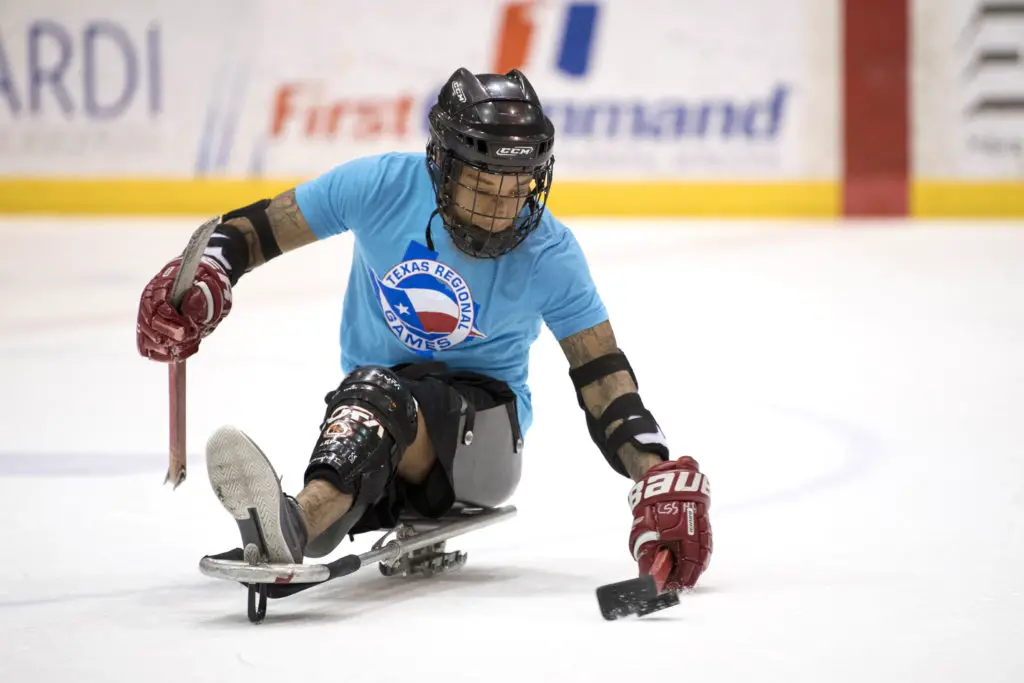 sled hockey athlete handling hockey puck on sit sled 