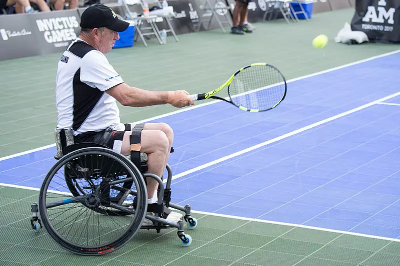 adaptive sport wheelchair tennis, man swinging and striking tennis ball