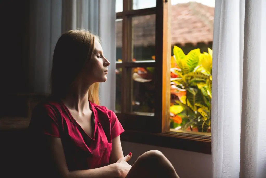 woman meditating near an open window