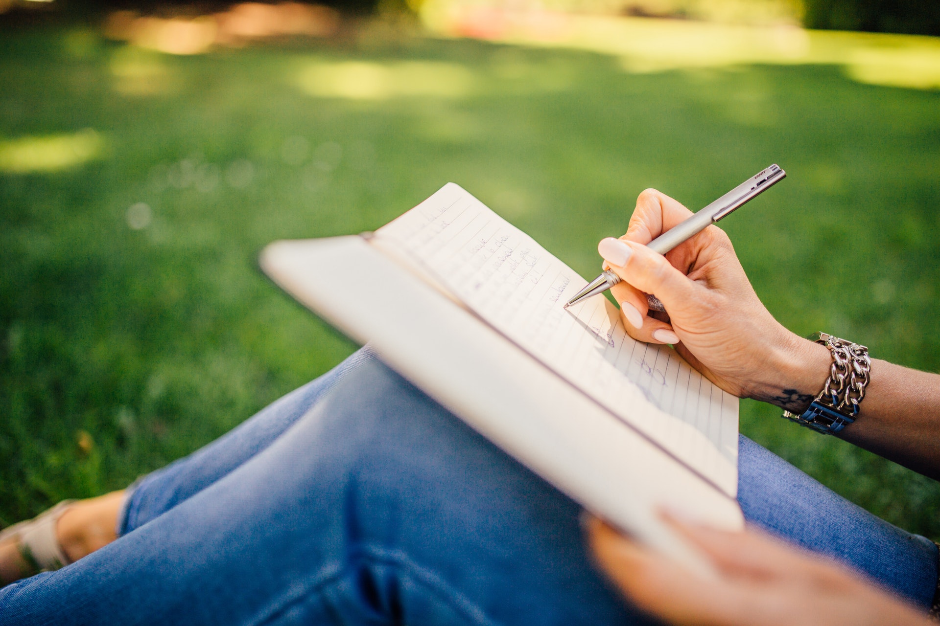 woman journaling outdoors, close up of hands and journal