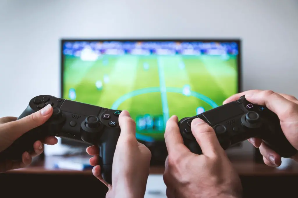best hobbies for couples include playing video games together. Image of two PS4 controllers with soccer video game in the background