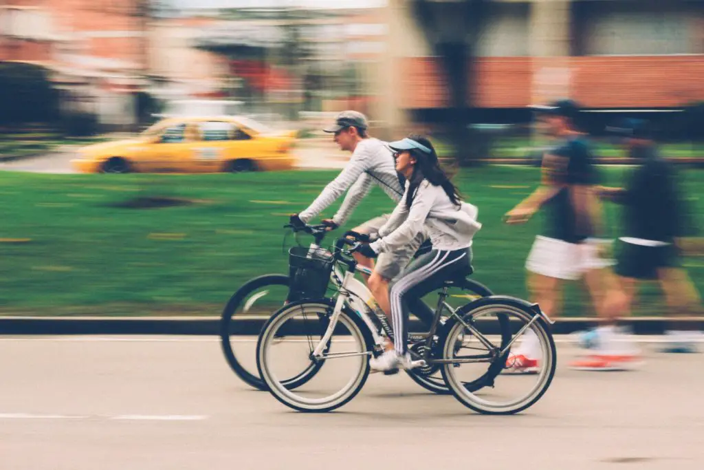 best hobbies for couples include bike riding; couple bike riding down street with blurred background