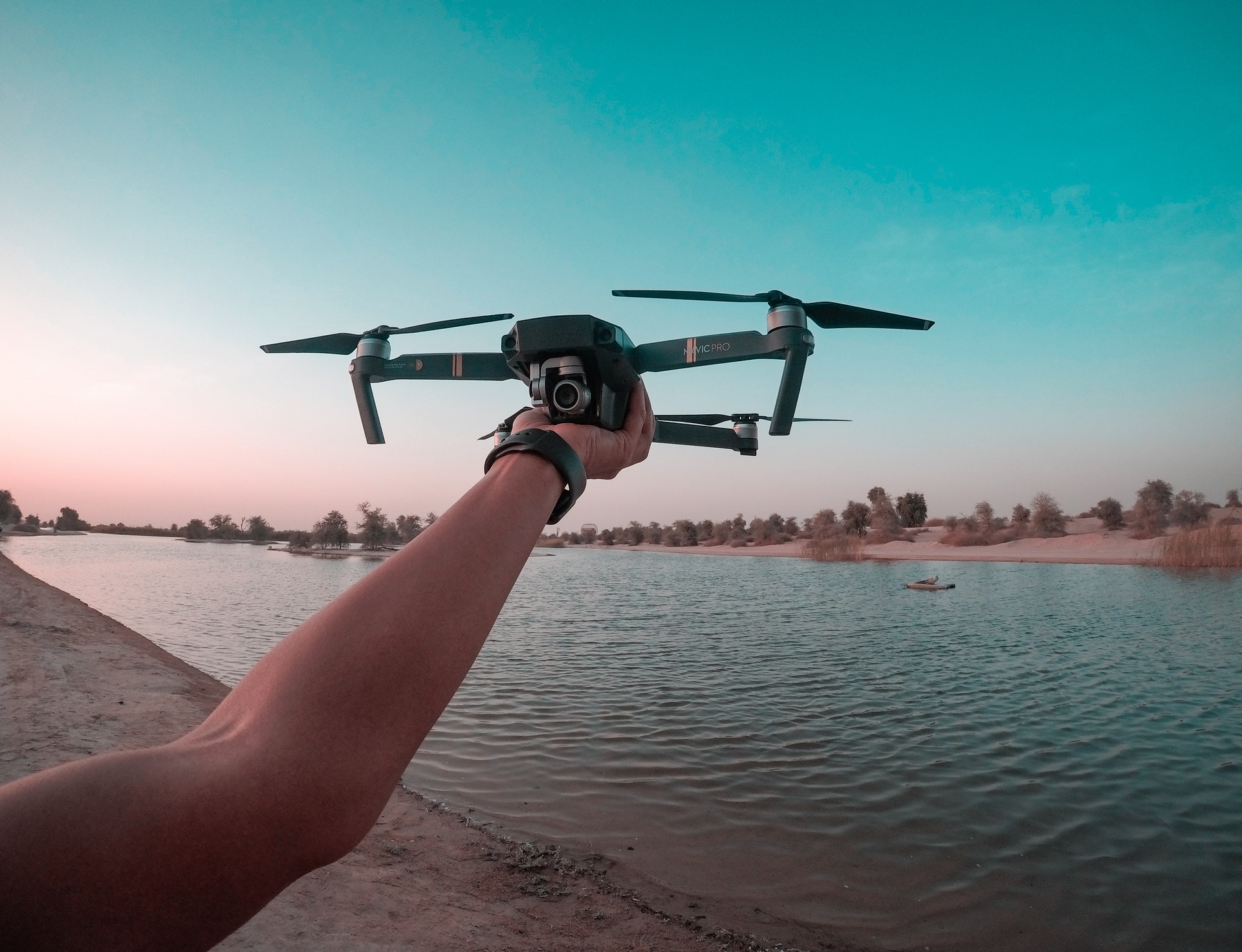 drone flying hobby, hand hold drone before flying near lake at sunset