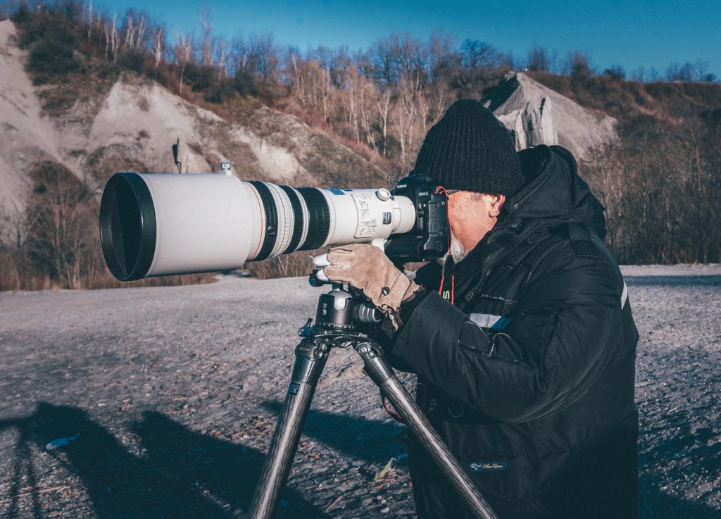 man with camera taking photo with large lens; photography hobby