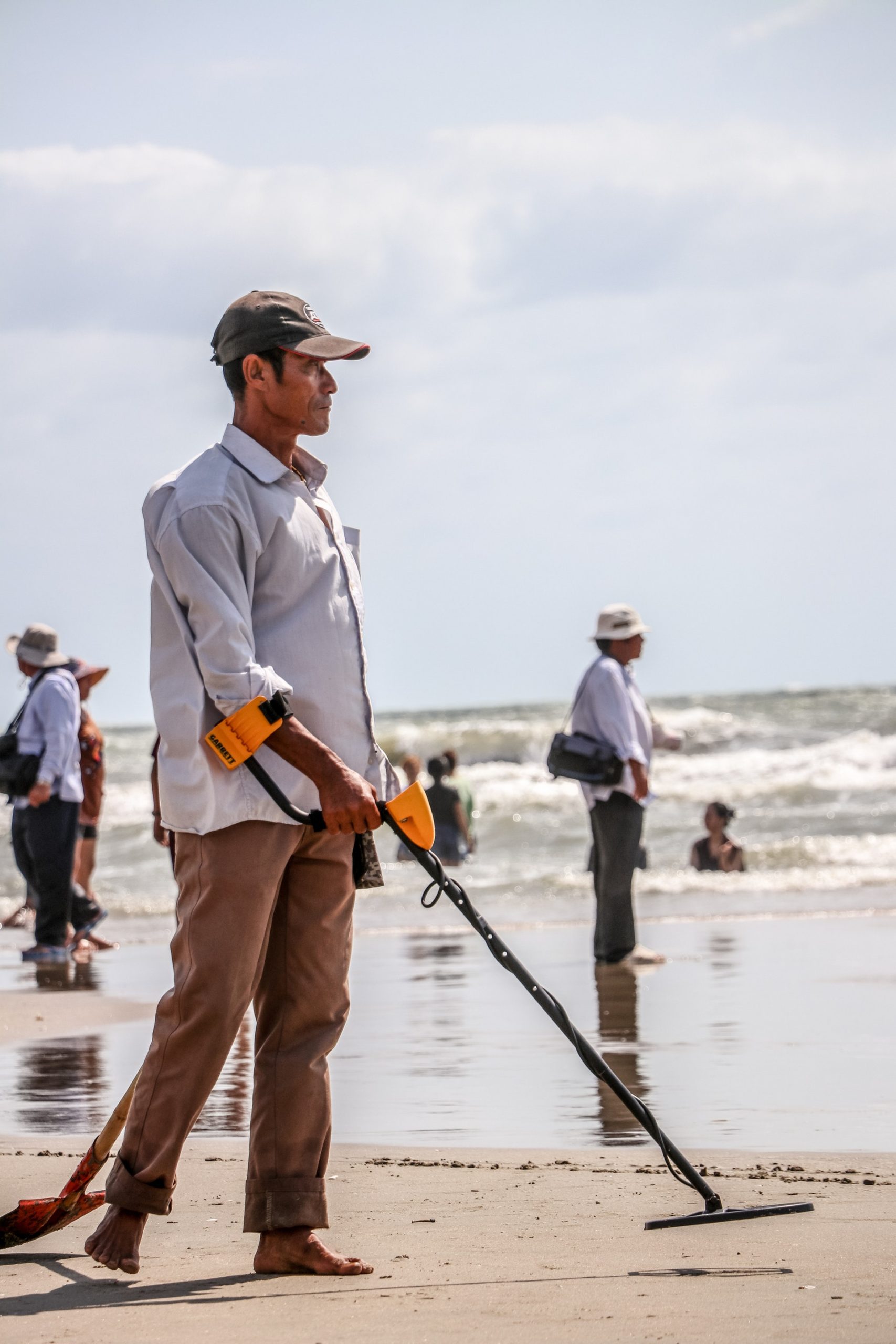 man metal detecting on the beach