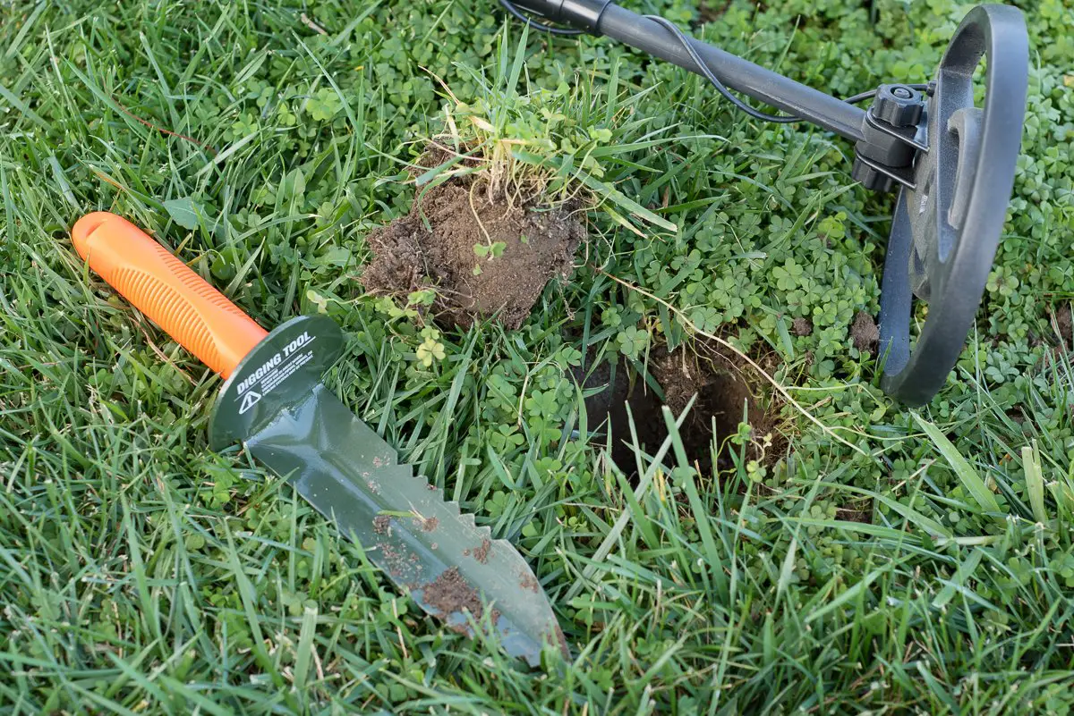 metal detector digging tool to find buried treasures. Grass, and small hand shovel with orange handle