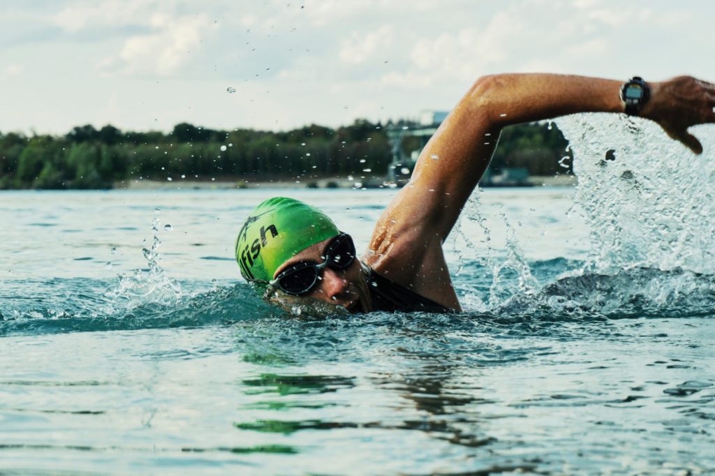 swimming hobby for older men; man outdoor swimming taking a breath looking for the camera