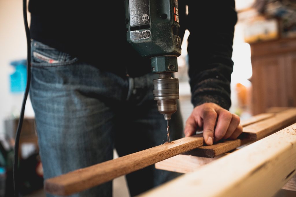 man holding a piece of wood; screwing a hole.  Woodworking hobby