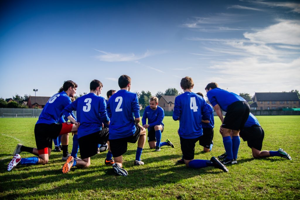 group of men playing soccer, group meeting in a circle talking between game. adult sports league as one of best hobbies for extroverts