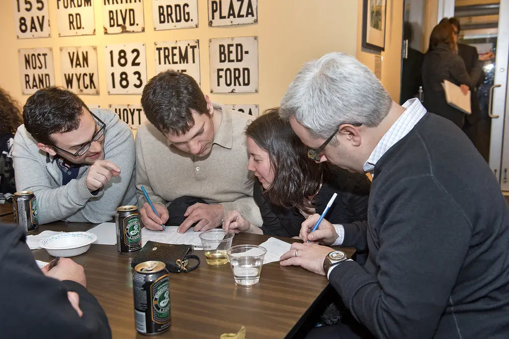 group of adults gathered at a table answering questions at trivia night.  Trivia nights are one of the best hobbies for extroverts for a social night out
