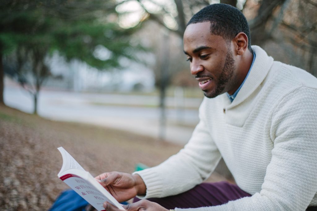 home hobbies learning a language, man reading a book outdoors