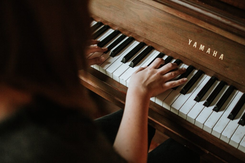 quarantine hobbies for home, woman learning the piano overhead view