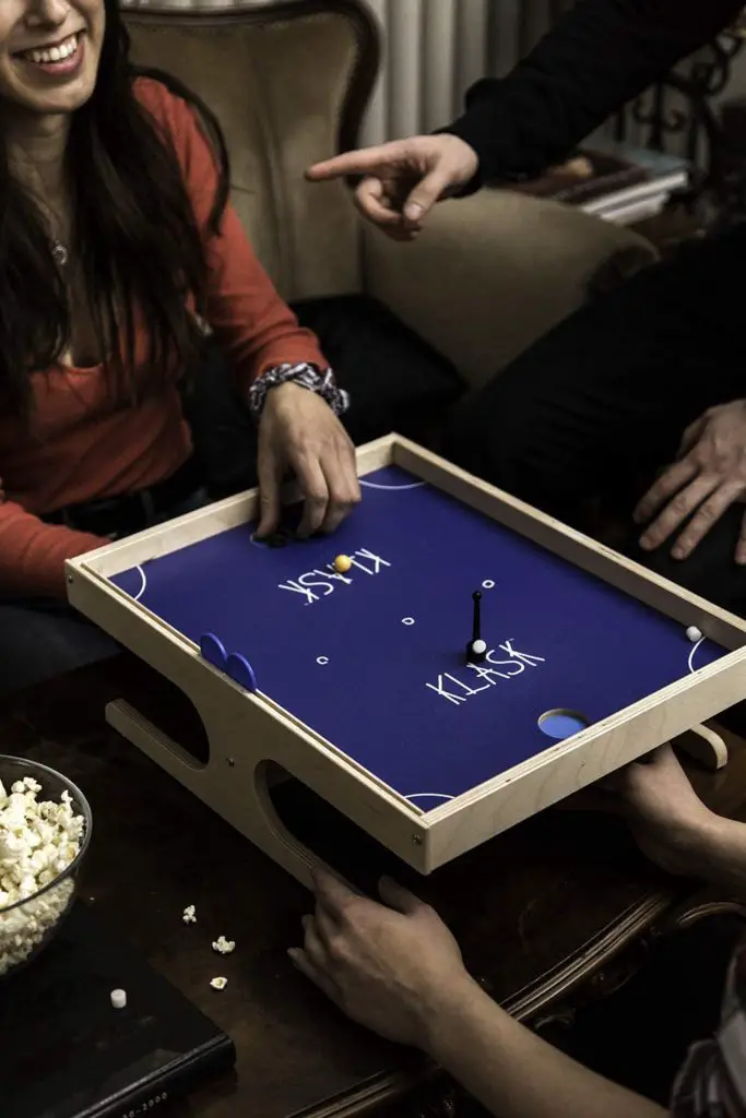 Klask tabletop game magnetic hockey style game; view of family gameplay