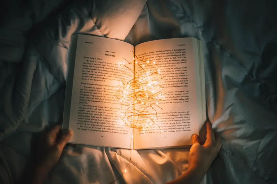 overhead view of book on bed with light string in the book