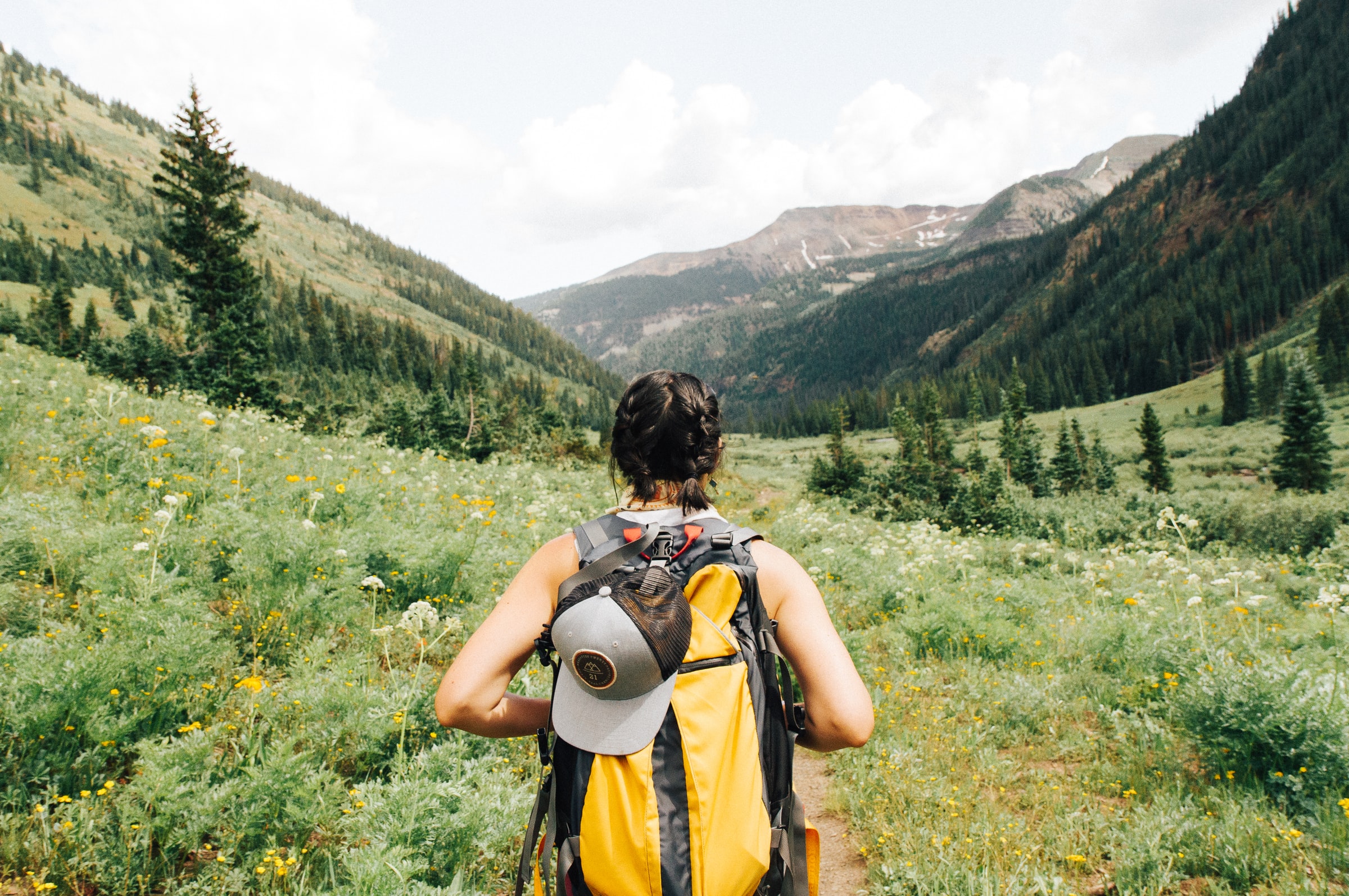 back view of woman headed down a hiking path headed towards mountain