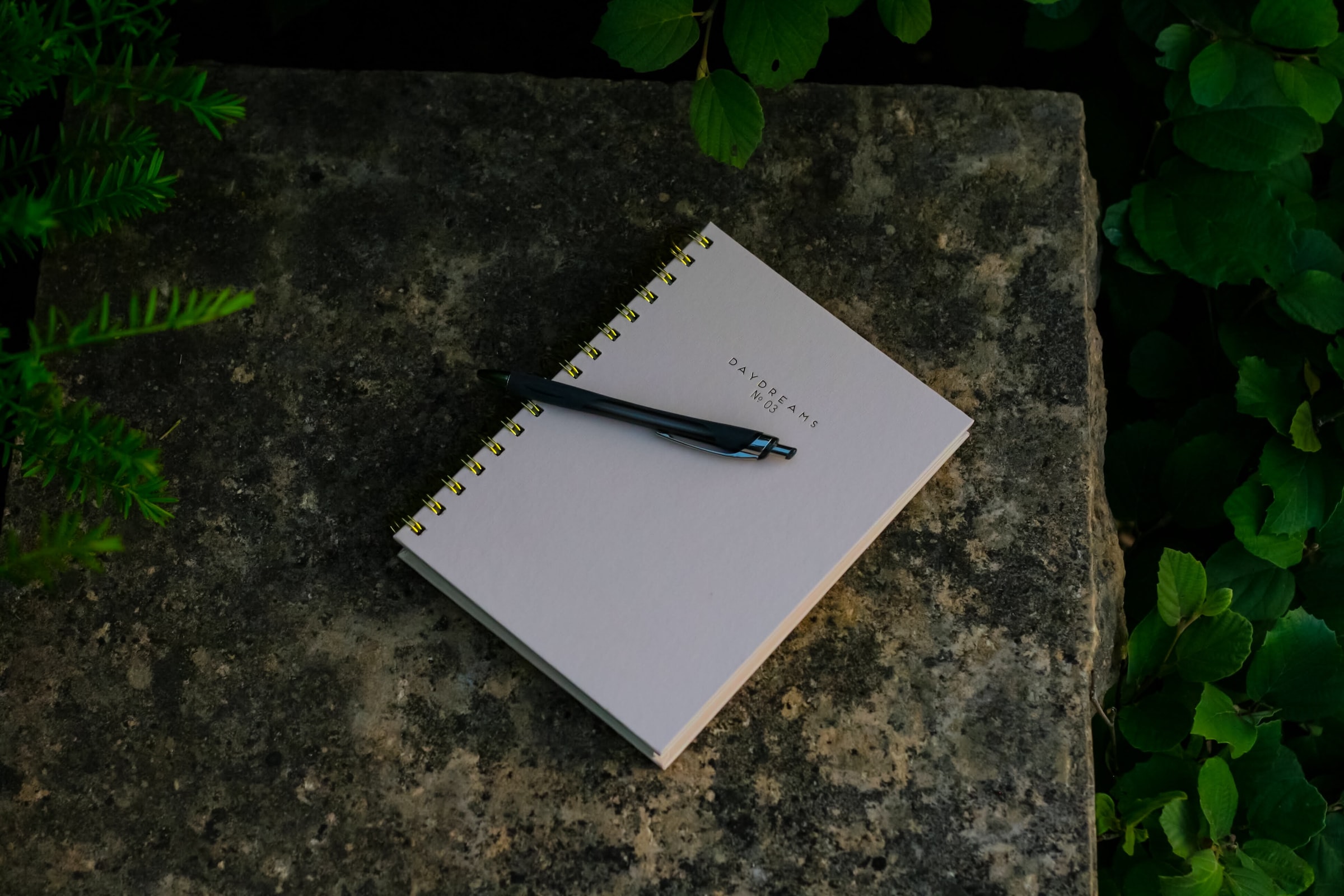 overhead view of journal on cement bench with pen outdoors