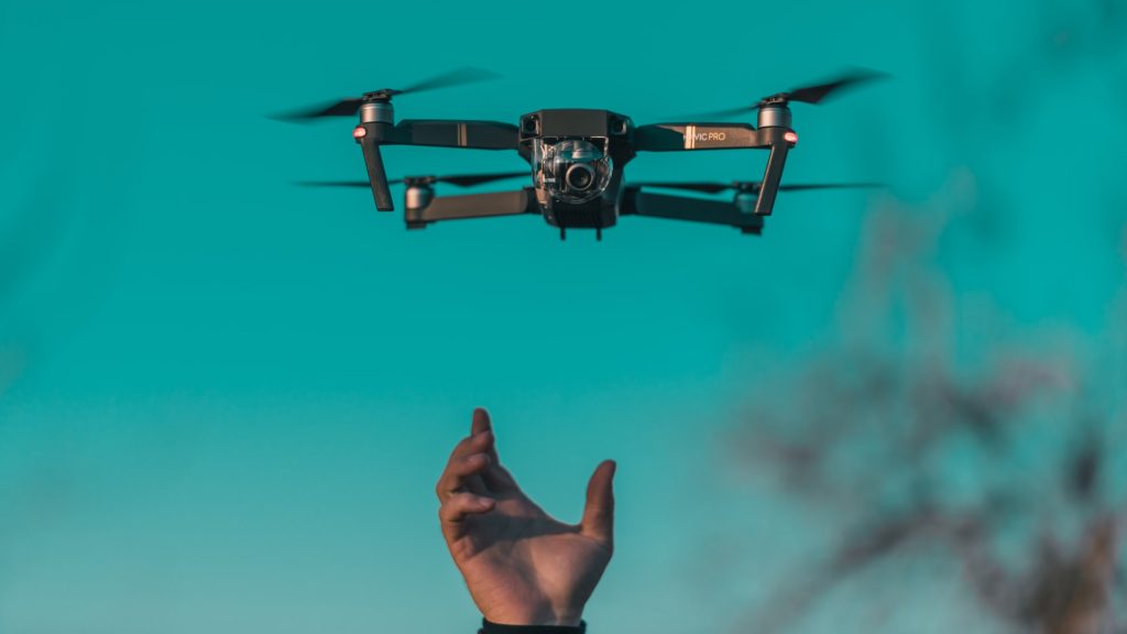 Man putting hand up towards flying drone