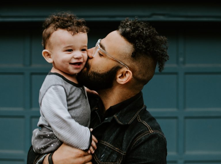 father and infant son, against a green background