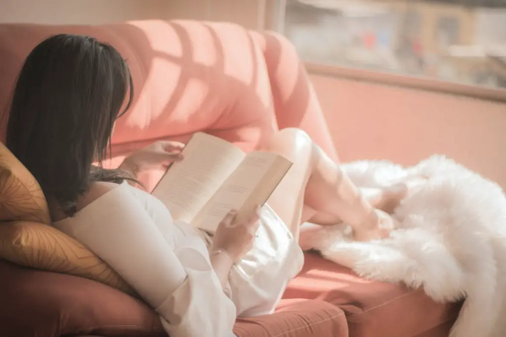 woman on a pink couch reading a book