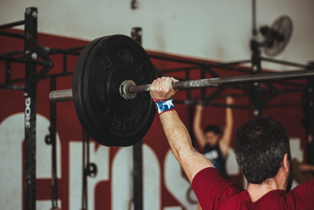 hobbies for weight loss include weight lifting. Pictures is a man raising a weights above his head