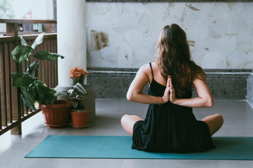 woman sitting on a yoga mat with hands behind her back. Hobbies for pregnant women include meditation and mindfulness practices.