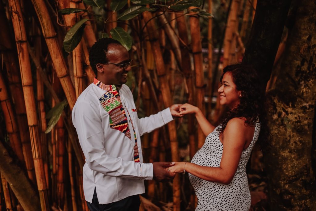 photo of smiling pregnant couple holding hands outdoors