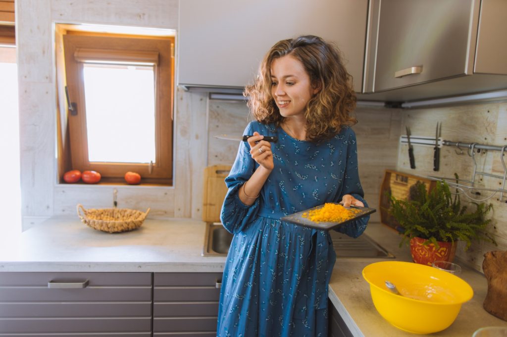 woman smiling chopping cheese for a meal in kitchen