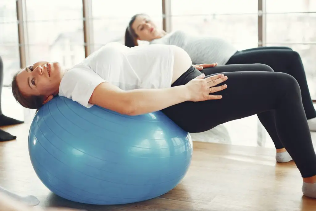 side view of pregnant woman laying on an exercise ball.  Exercise is a healthy hobby for pregnant women 