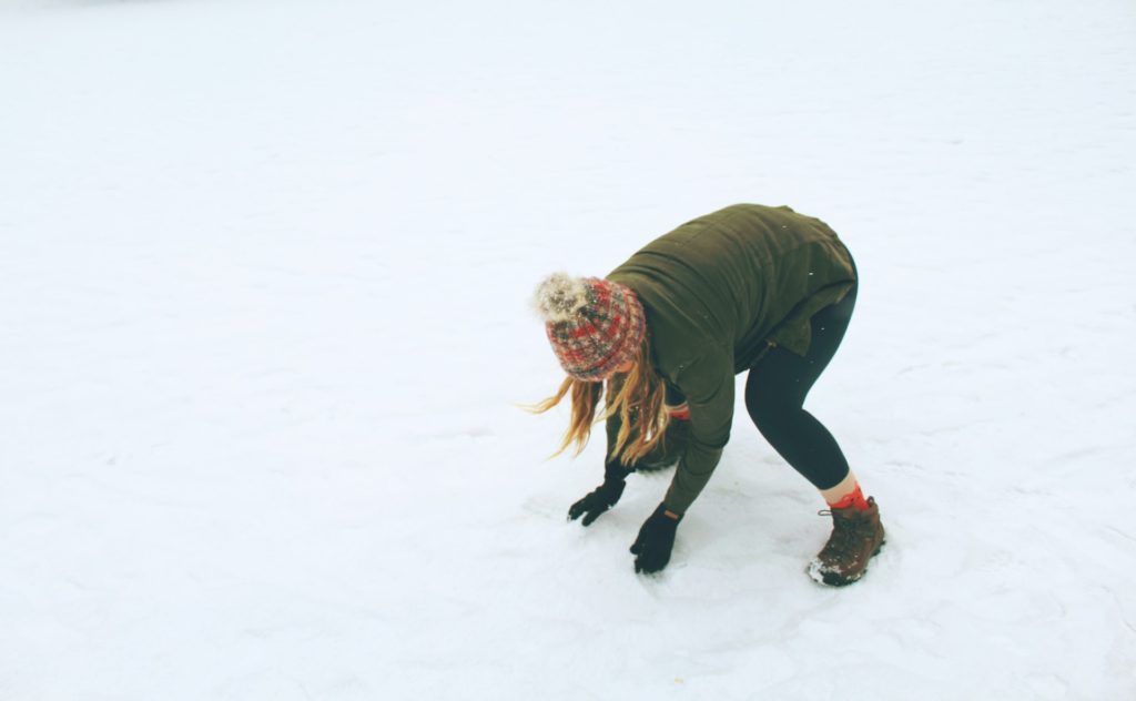 outdoor winter hobby snowball fight; woman making a snowball