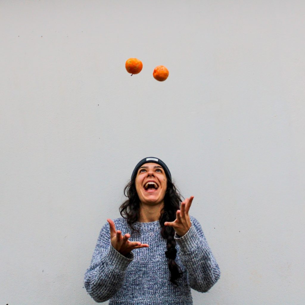 woman looking up at juggling balls against blank grey background