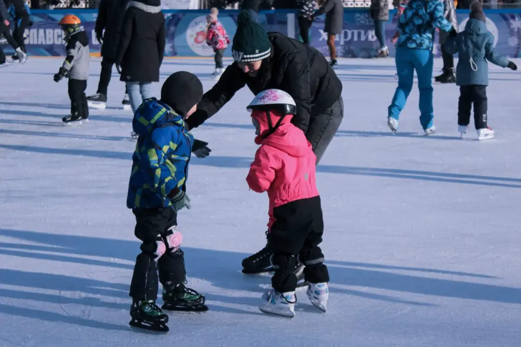 outdoor winter hobby iceskating; image of mother with two children iceskating