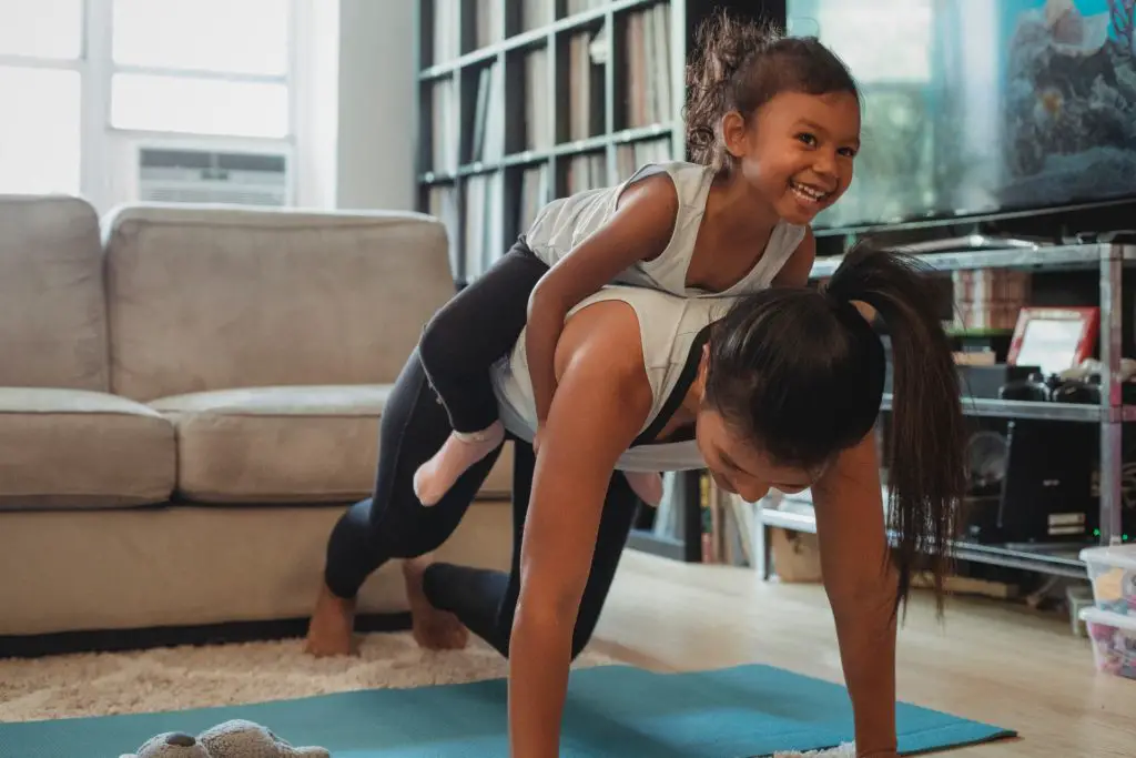 mother and daughter doing yoga in family room