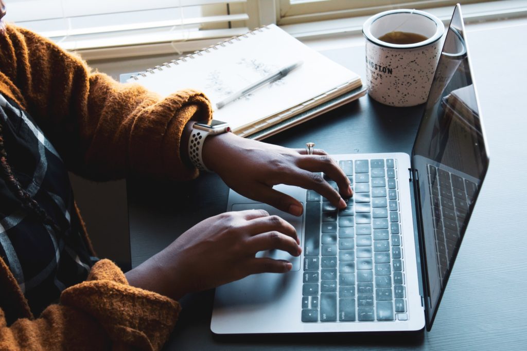 starting a blog, side-view of woman typing on a keyboard near a window