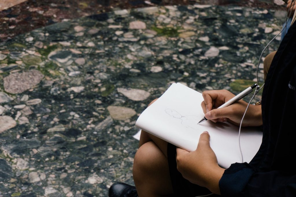 over-shoulder view of woman sketching outdoors