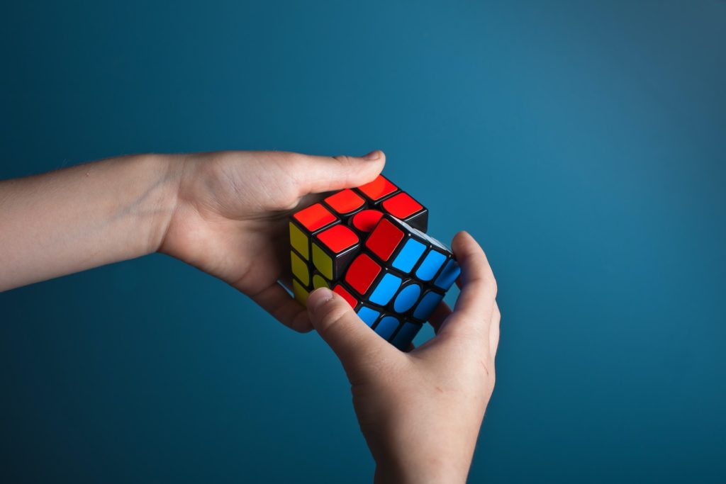 rubiks cube in hands against plain blue background