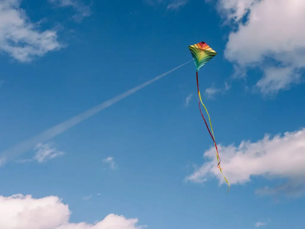 rainbow kite against blue sky with clouds