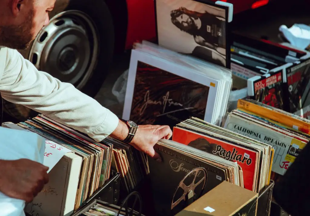 man looking through albums at a garage sale