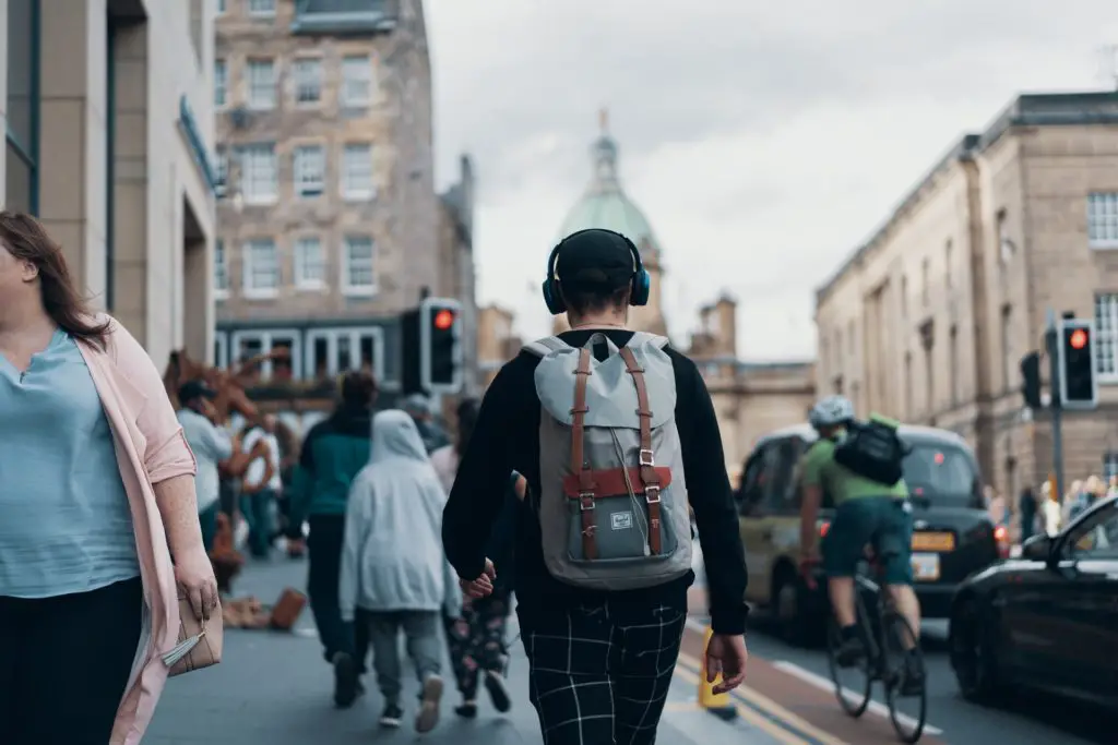 man in city area walking with headphones
